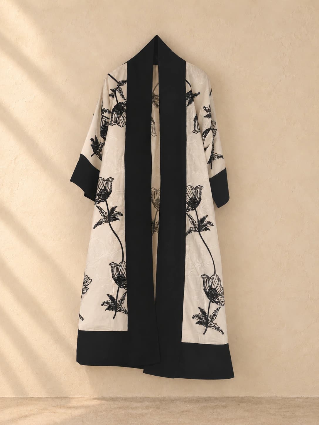 Kimono de lino con motivos florales negros sobre fondo marfil y bandas negras. Imagen editada con IA.